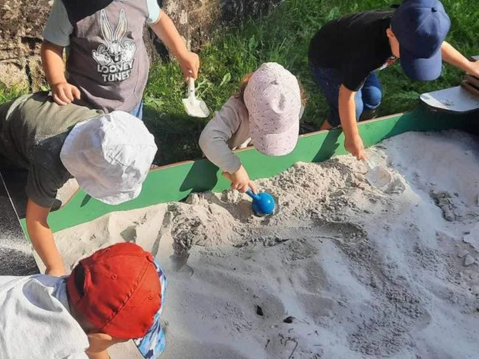 Plusieurs enfants jouent librement dans un bac à sable de la crèche Les Petits Tournesols.